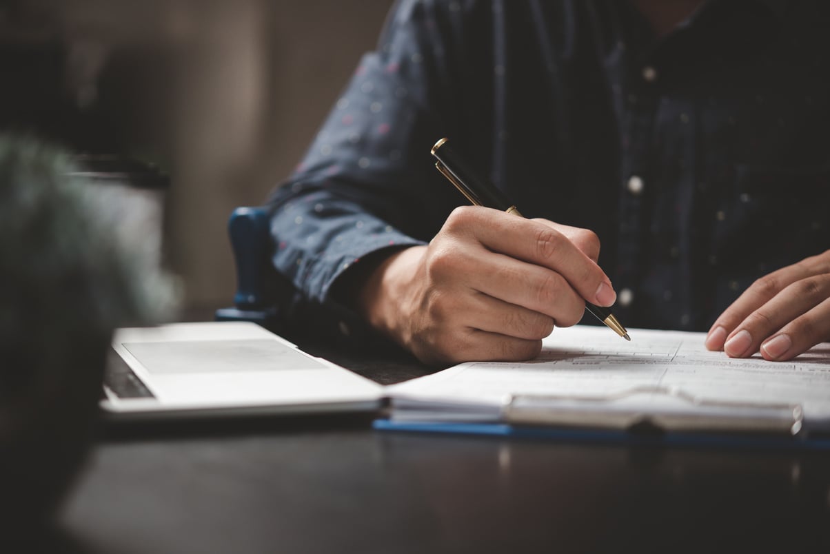 Hand holding pen writing paperwork business document financial i